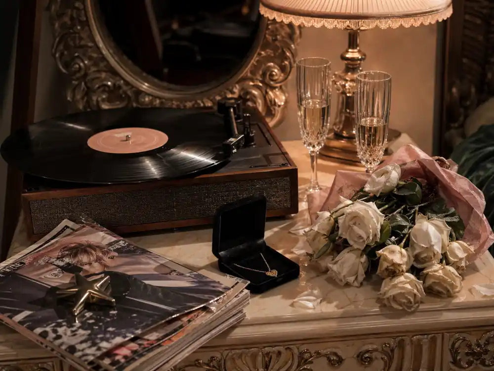 A vintage record player, champagne flutes, a velvet jewellery box and wilting white roses