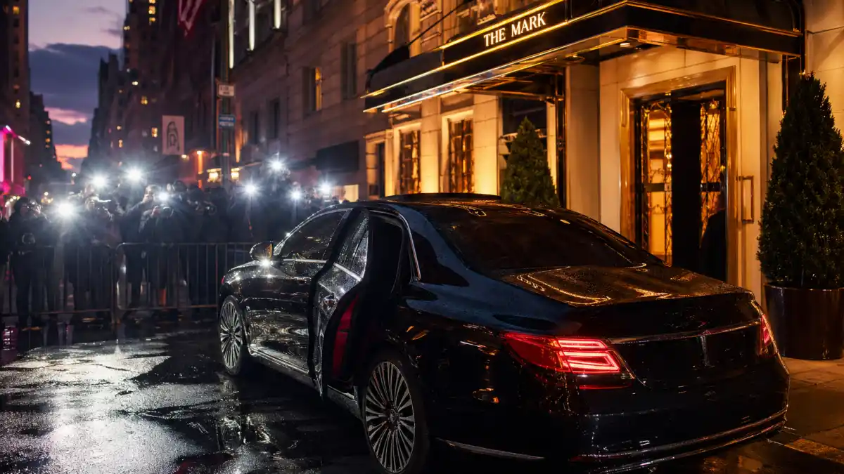 A luxury black sedan with the door open at a Manhattan hotel entrance with paparazzi flashes — the kind of nighttime arrival Taylor Swift has become known for in New York City