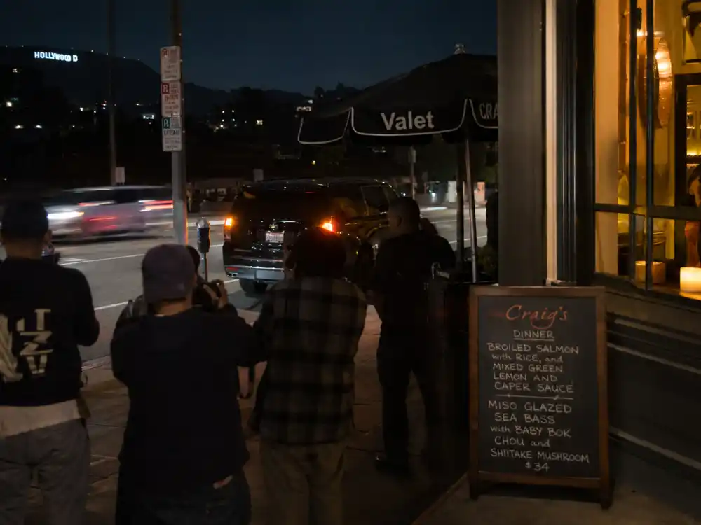 An upscale Los Angeles restaurant exterior at night with paparazzi outside