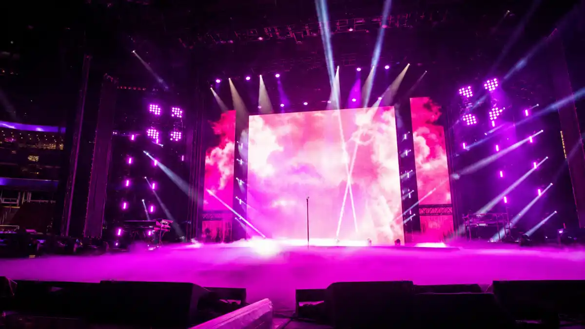 Concert stage with pink and purple lighting representing Ariana Grande dating history through her music career