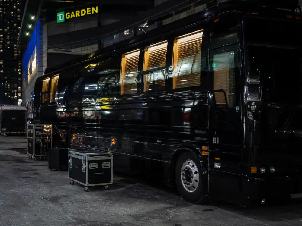Concert tour bus parked outside an arena at night during Billie Eilish Hit Me Hard and Soft tour