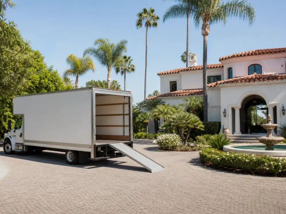 Large white moving truck parked outside a Mediterranean California estate symbolizing the celebrities who left California