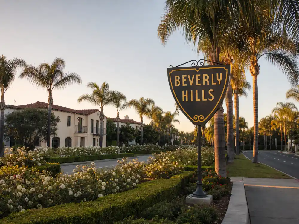 Iconic Beverly Hills sign with palm trees and luxury car at golden hour where celebrities who live in Beverly Hills are often photographed