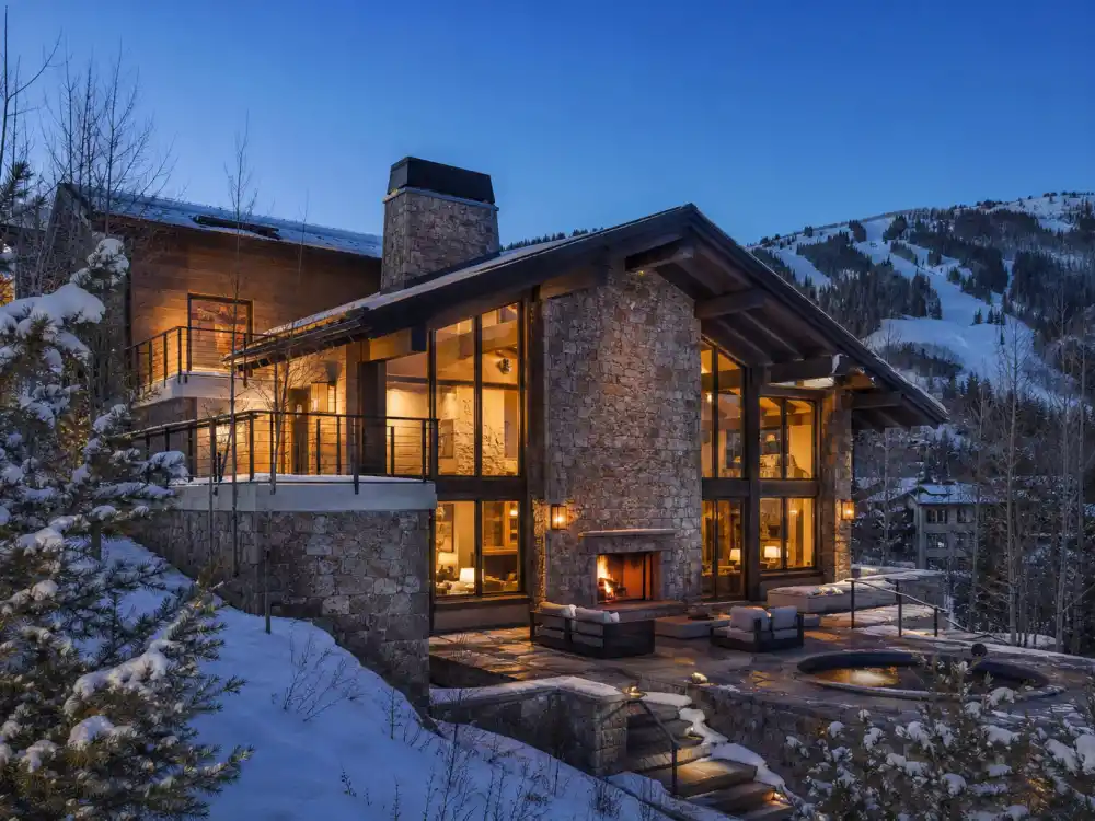 Aspen ski chalet style celebrity vacation homes with stone fireplace and snowy mountains