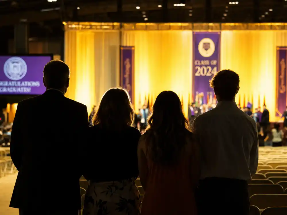 Family of four silhouettes watching Apple Martin Vanderbilt graduation ceremony stage from the audience