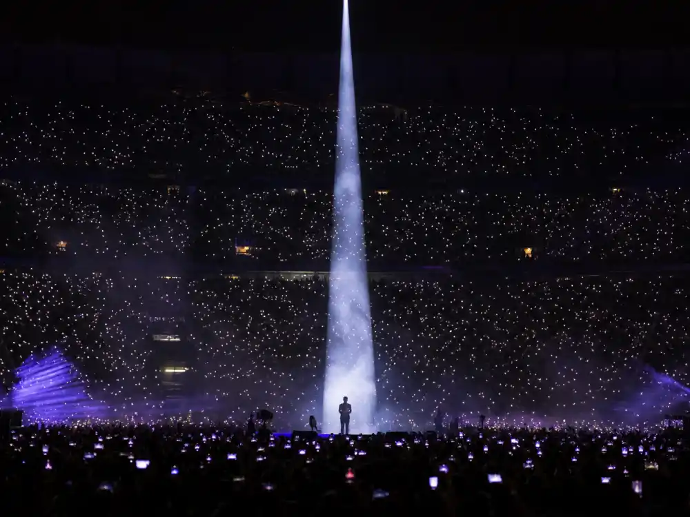 Concert stage with dramatic spotlight representing Harry Styles dating history and music career