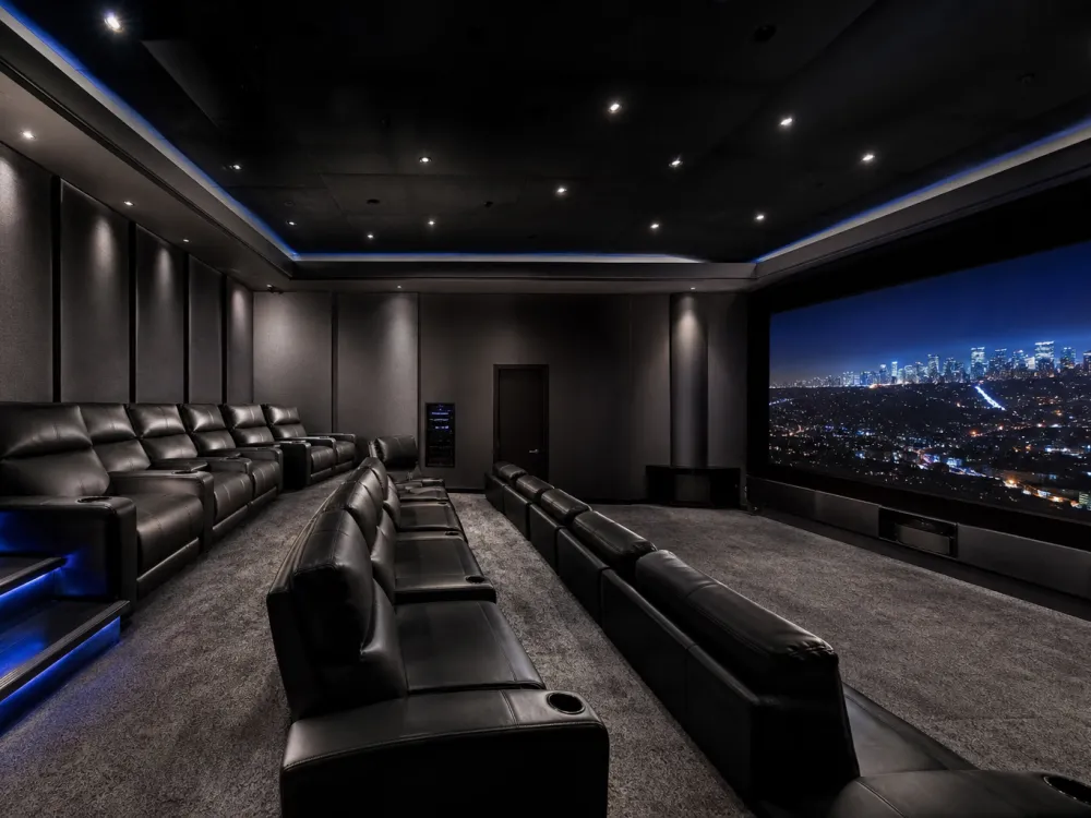 Jay-Z and Beyoncé Bel Air modern home theater with black leather recliners and blue LED step lighting overlooking the LA skyline