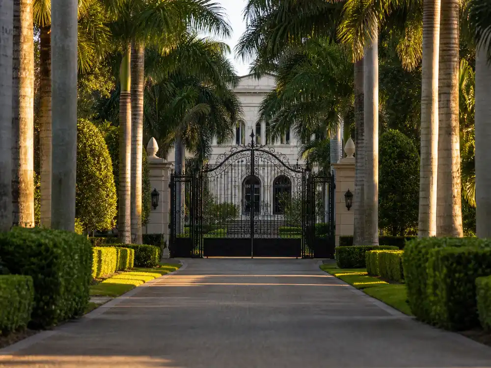 Jennifer Lopez Bel Air mansion iron gate entry with long driveway and lush hedges