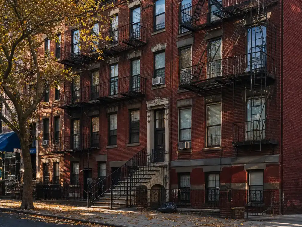 Brick four-story walk-up apartment building in the Bronx with iron fire escapes — the celebrity childhood home where Jennifer Lopez grew up
