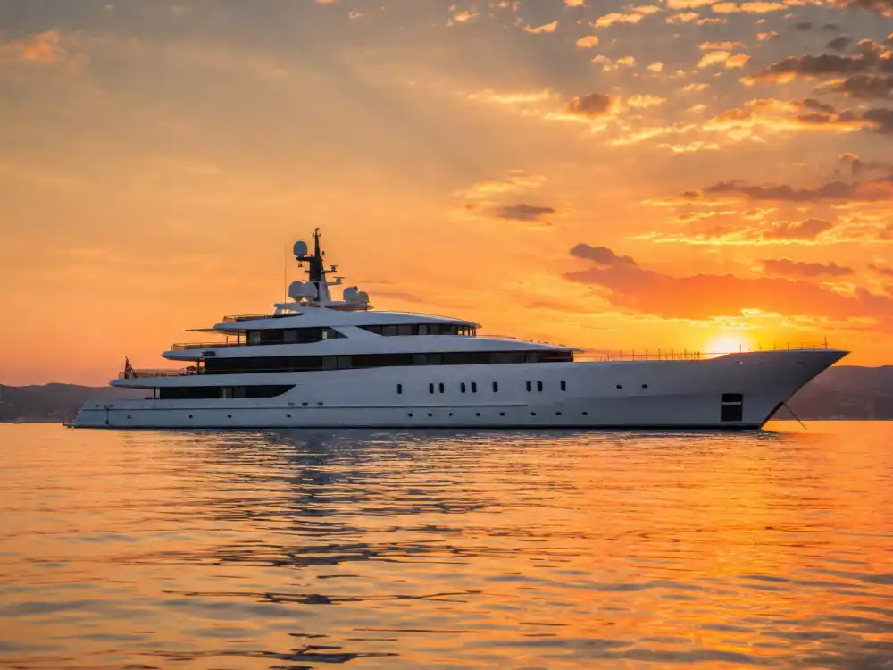 Luxury mega yacht at sea during a golden sunset, the kind of vessel seen in Leonardo DiCaprio relationship photos