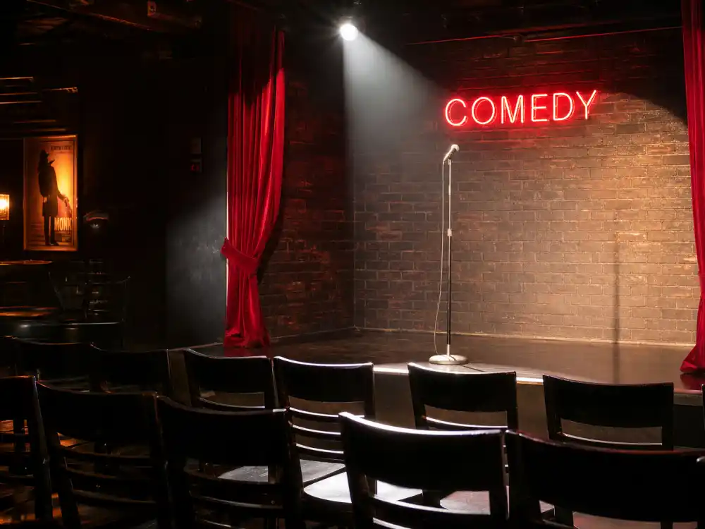 Stand-up comedy club with microphone and spotlight representing Pete Davidson relationships and career