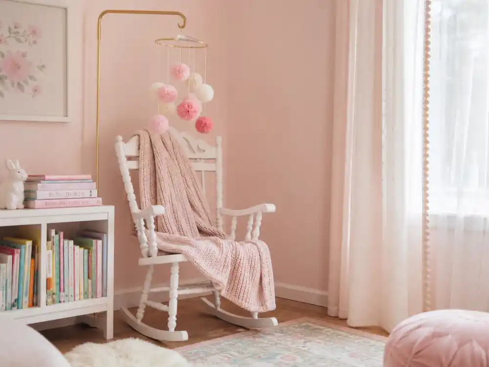 Pink nursery with white rocking chair representing Beanie Feldstein pregnant baby on the way