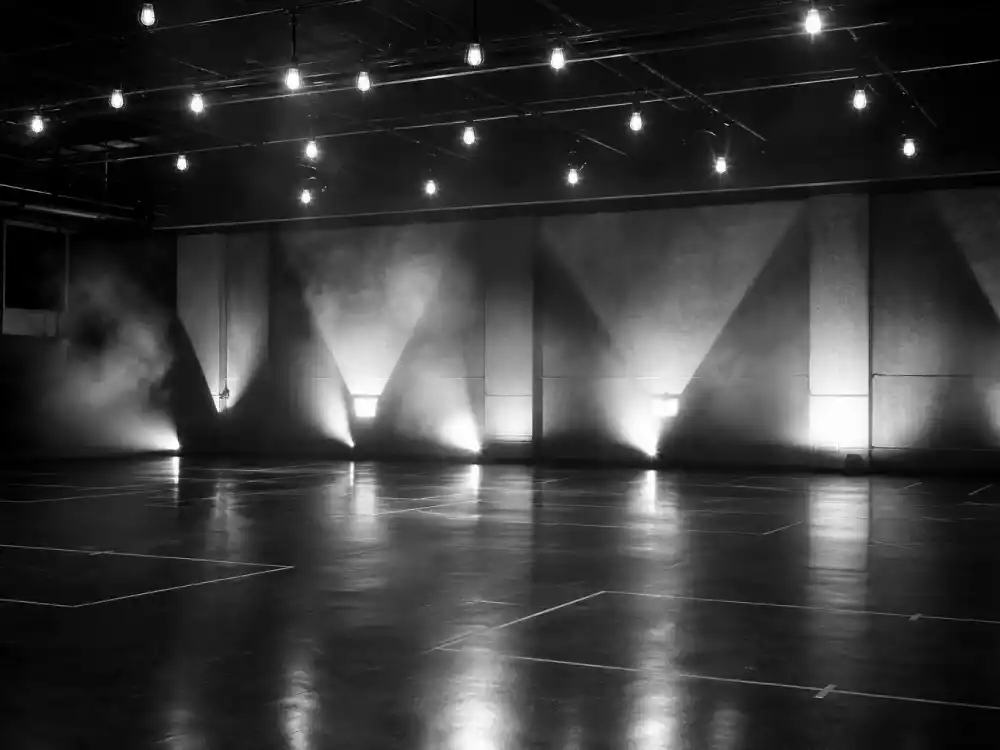 Black-and-white industrial stage set with overhead lighting evoking the Rhythm Nation 1814 military choreography aesthetic celebrated at the Janet Jackson Grammy Hall of Fame