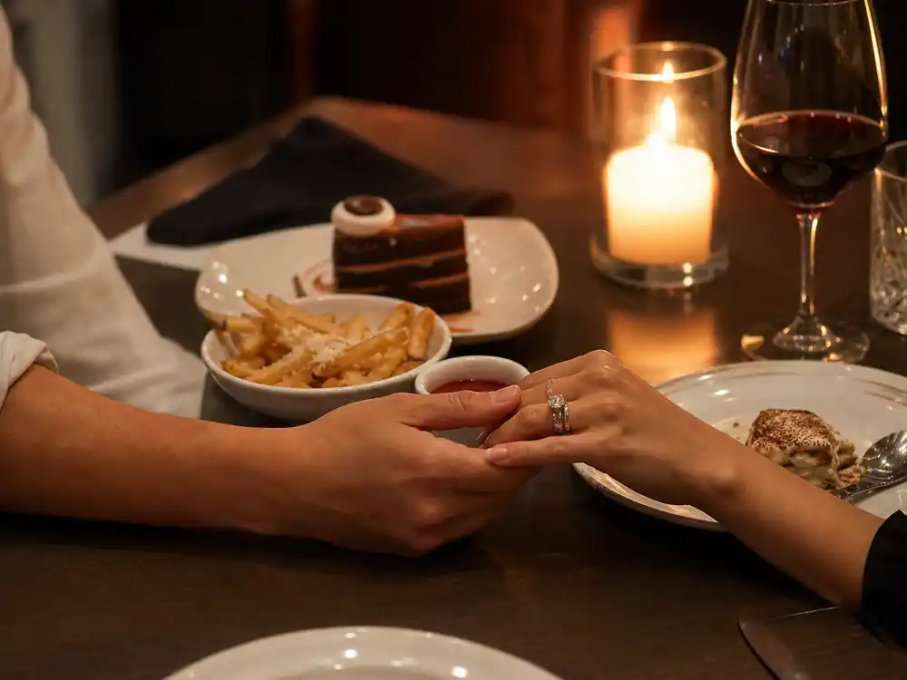 Selena Gomez Benny Blanco relationship dynamic represented by anonymous couple hands at dinner.