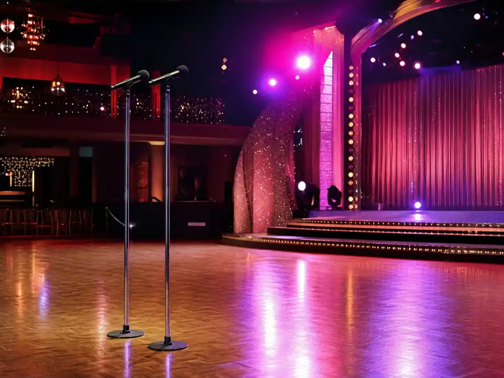 Two empty chrome microphones on a glittery ballroom stage representing the Tess Daly Vernon Kay UK broadcasting power couple after their split announcement