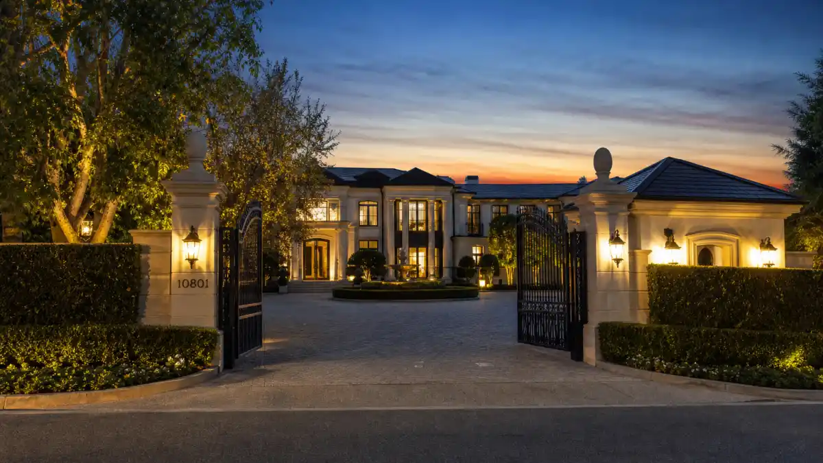 Where does Justin Bieber live — contemporary Beverly Park mansion behind double iron gates with security booth at dusk