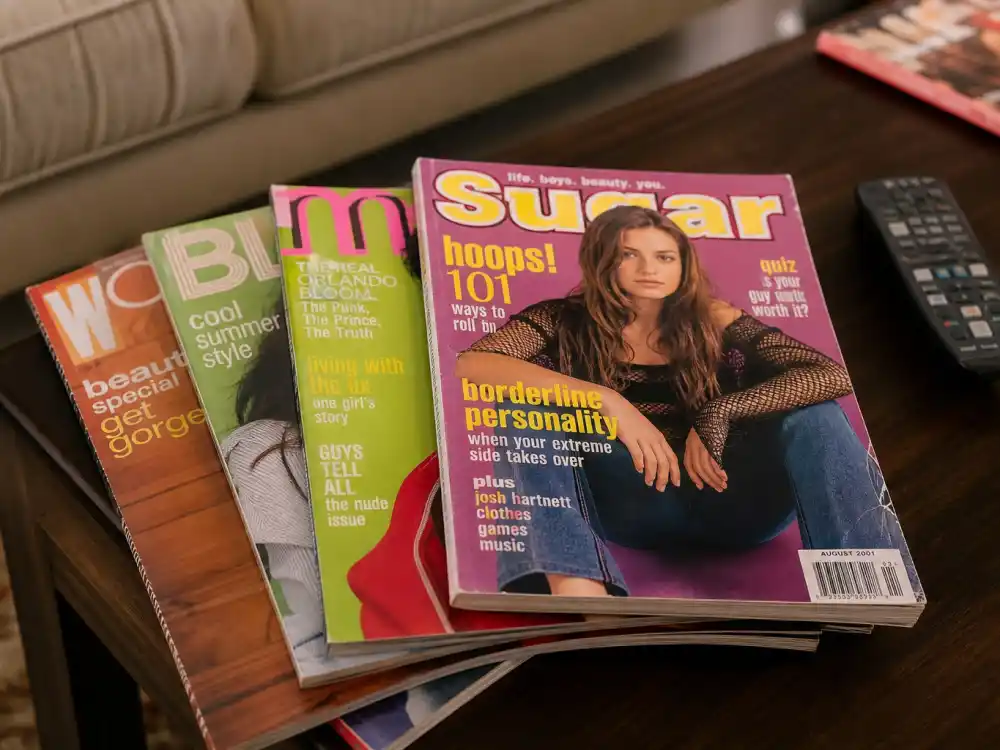Vintage early-2000s teen magazines on coffee table behind 2000s teen stars where are they now searches