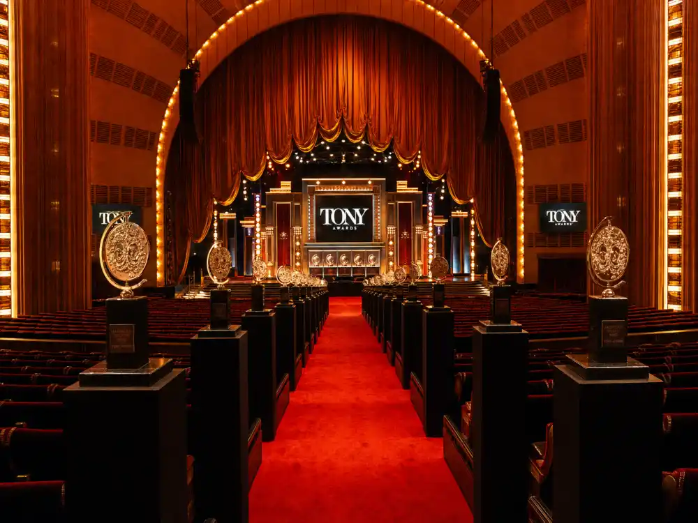 Grand Art Deco awards theatre aisle with Tony trophies evoking June ceremonies for actors who won both a Tony and an Oscar