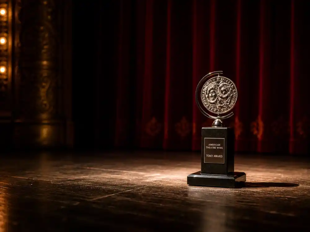 Broadway stage spotlight with Tony Award statuette where actors who won the triple crown of acting earned their theatre leg