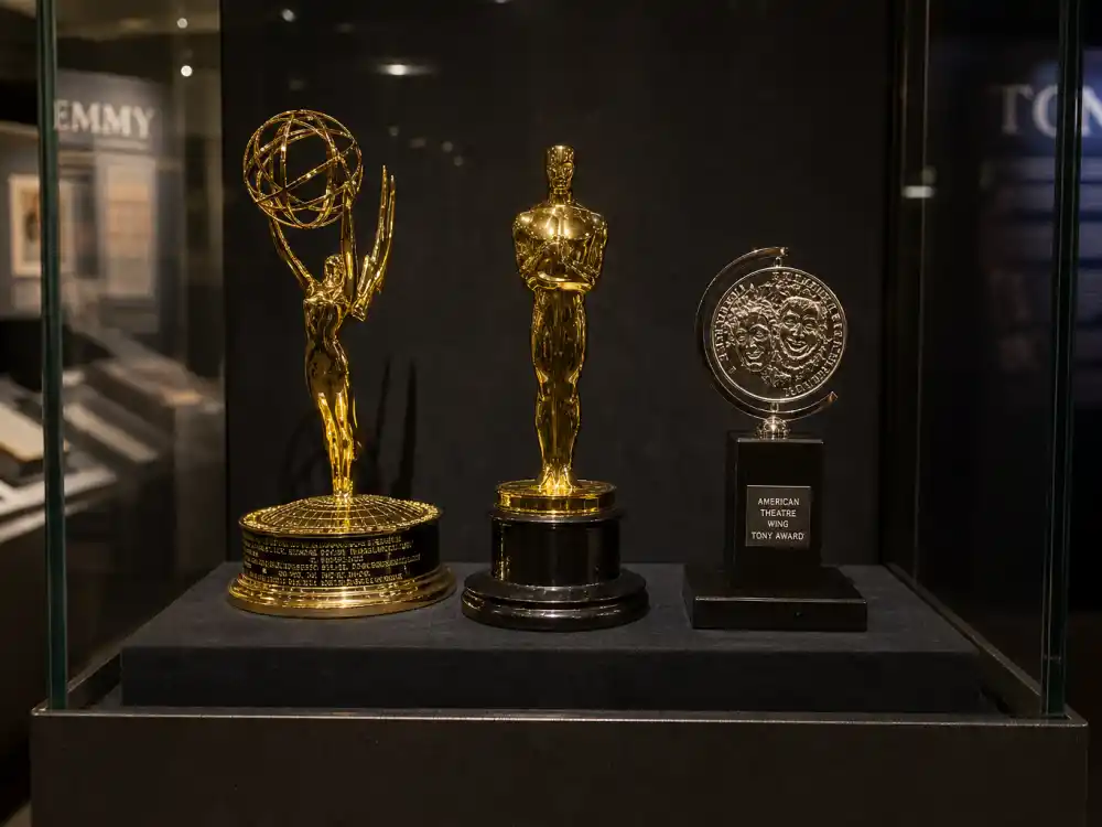Museum display of Oscar Emmy and Tony trophies documenting actors who won the triple crown of acting across film television and Broadway