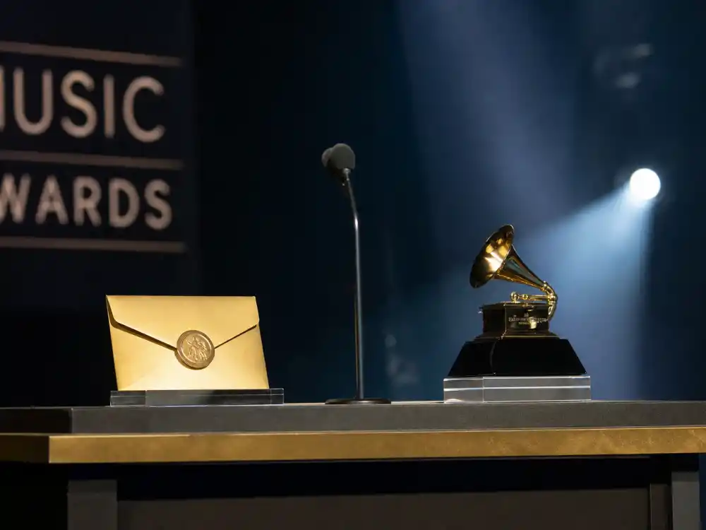 Sealed envelope beside golden trophy on AMA ceremony podium before Artist of the Year reveal updates the winners list