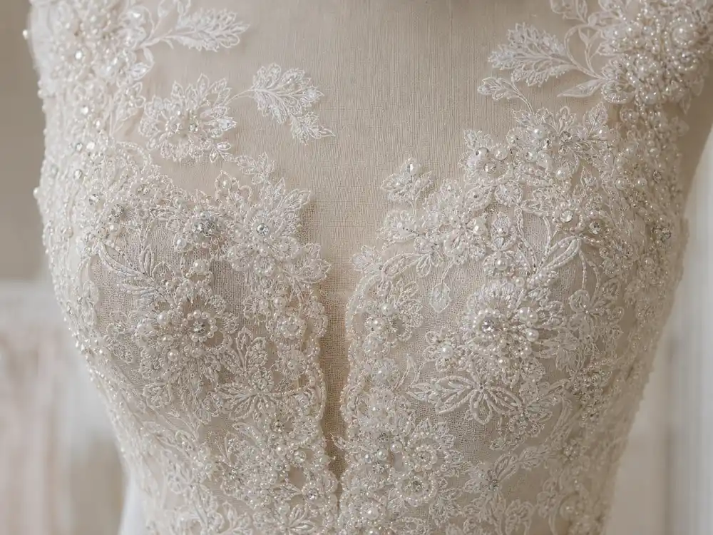 Hand-embroidered pearls and diamanté on ivory French Chantilly lace bodice defining Amal Clooney wedding dress Oscar de la Renta couture signature detail