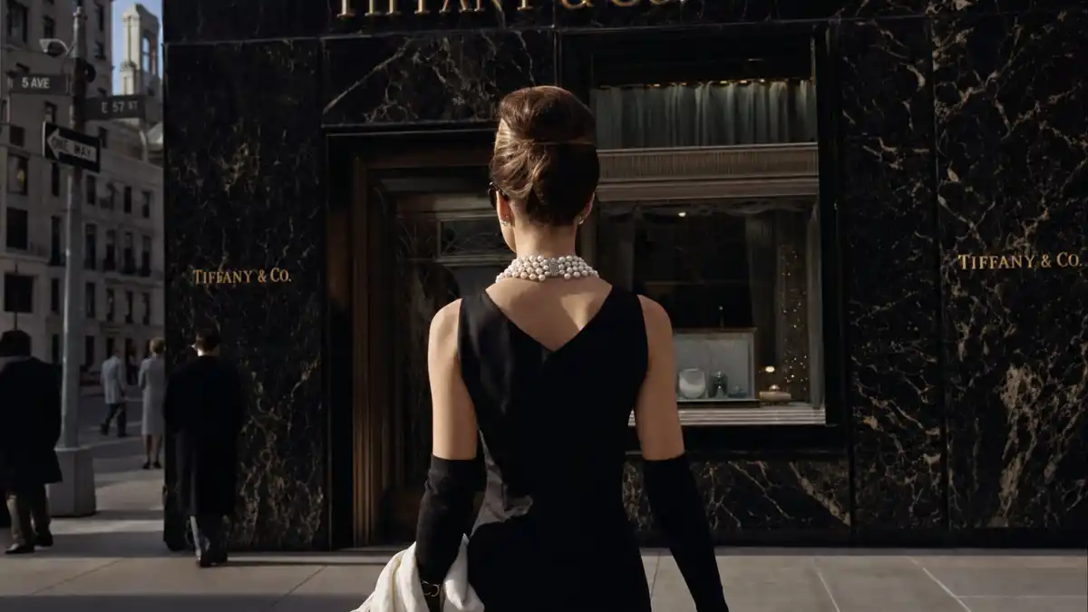 Audrey Hepburn little black dress Givenchy — iconic sleeveless sheath with pearl necklace photographed from behind outside Tiffany storefront in Breakfast at Tiffany's inspired scene