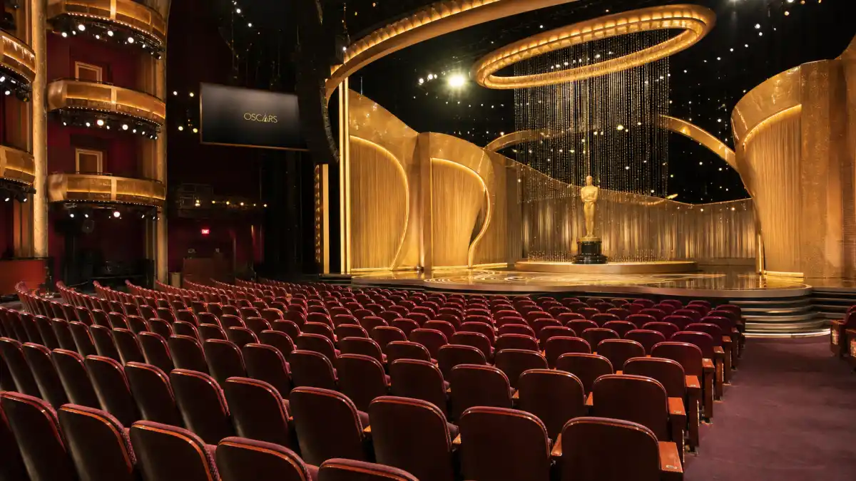 Award show etiquette rules celebrities follow — empty red velvet orchestra seats facing a golden Oscar-style awards stage in a grand theater auditorium