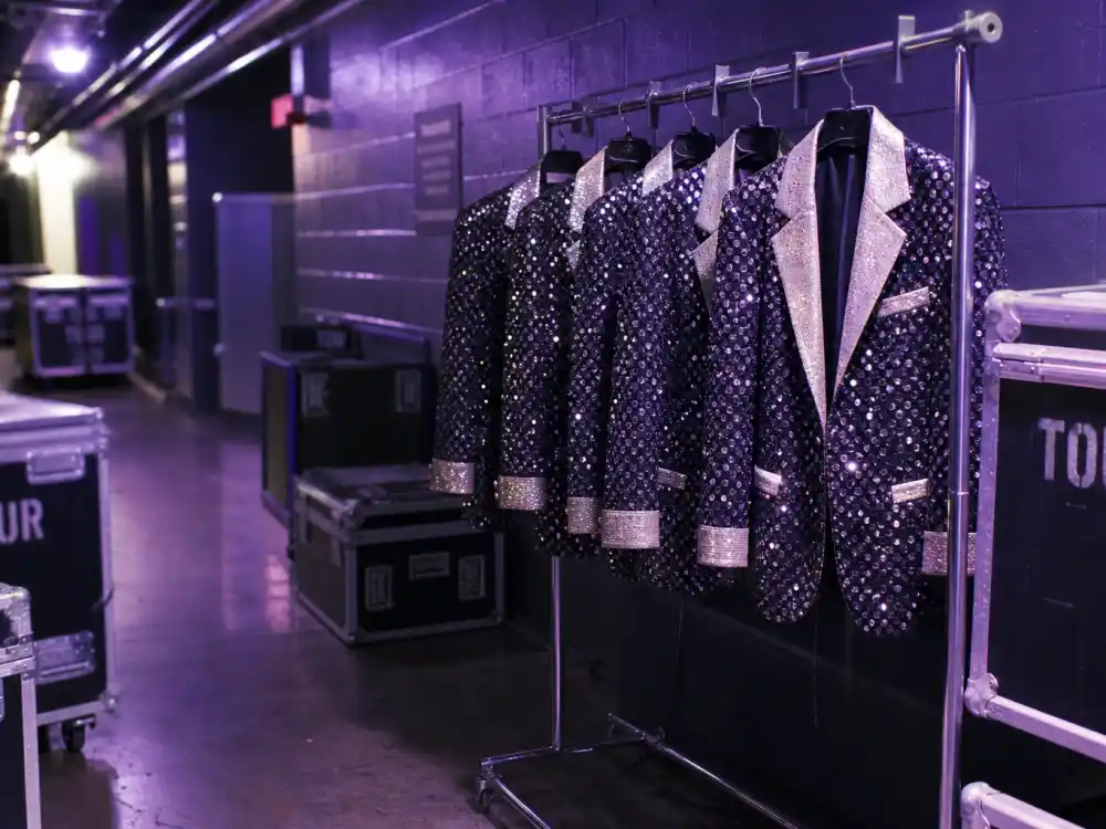 Backstage tour wardrobe racks with matching stage jackets evoking the Backstreet Boys Millennium tour era