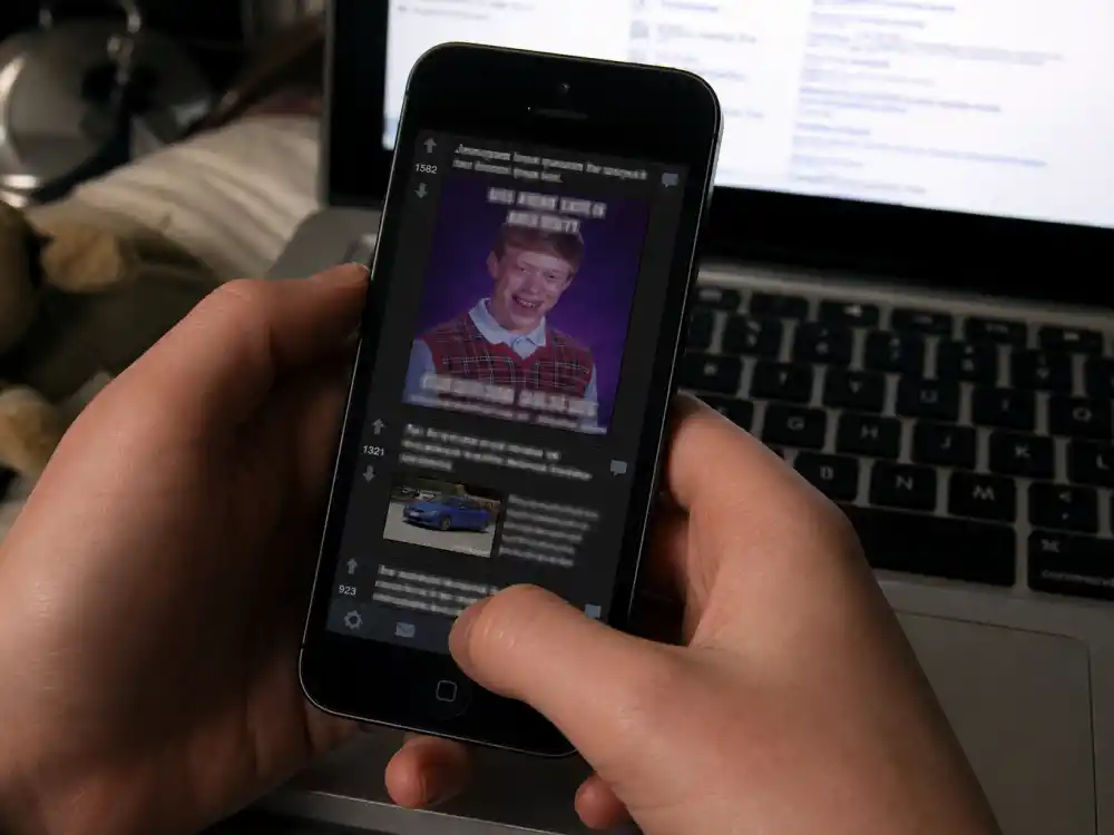 Smartphone Reddit feed on desk for what happened to Bad Luck Brian and the 2012 yearbook photo post