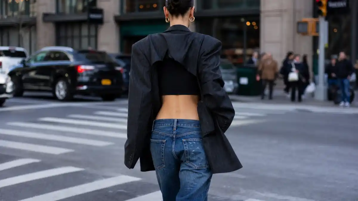 Bella Hadid off duty street style — low-rise wide jeans cropped tank oversized charcoal blazer and gold hoops on NYC crosswalk seen from behind