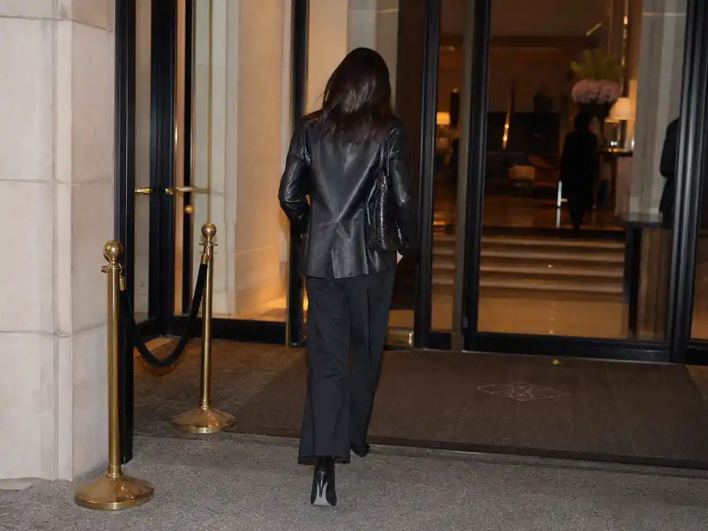 Hotel lobby exit with anonymous woman from behind in leather jacket and wide-leg trousers for best celebrity street style of all time paparazzi off-duty framing