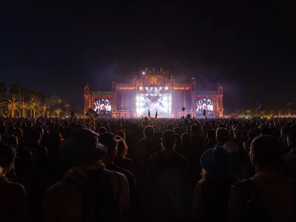 Festival audience silhouettes watching illuminated main stage at night in Beyonce Coachella kids cameo explained — verified 2018 Beychella crowd perspective per Elle