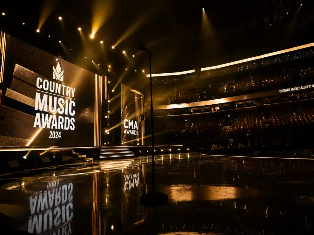 Empty arena stage with golden spotlights frames the live-television moments that built the Beyonce Grammy wins record from 2001 forward