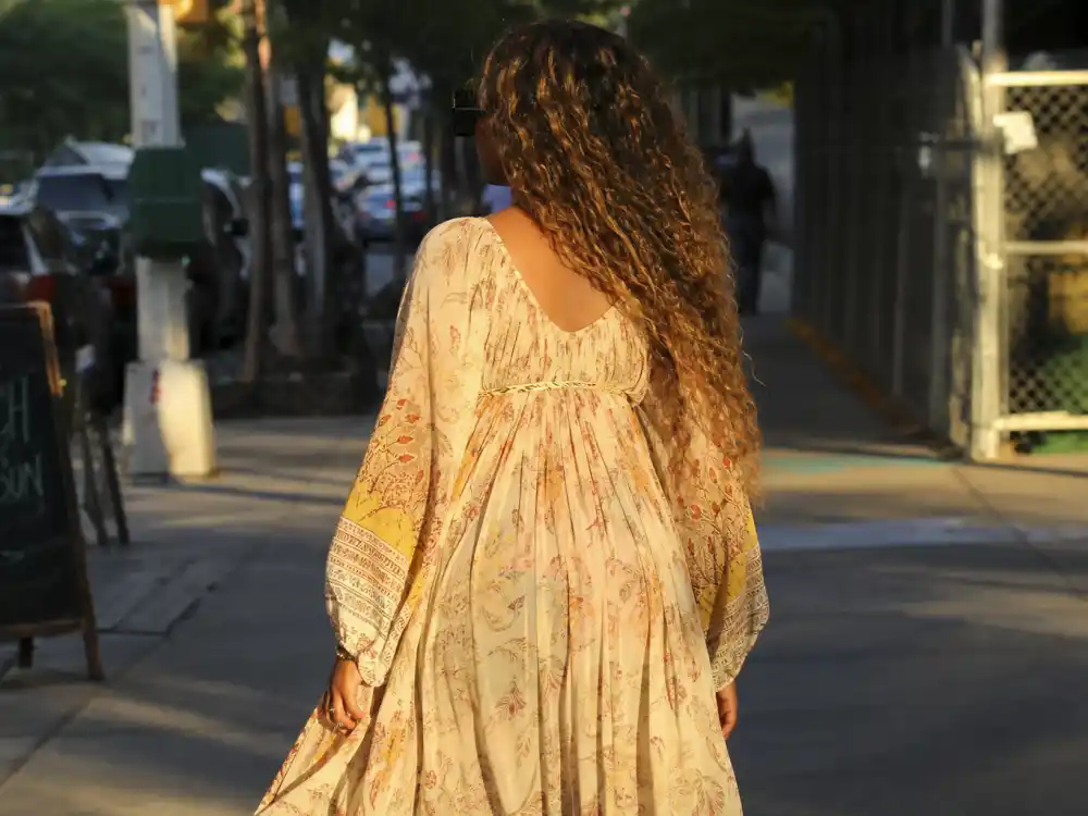 Anonymous pregnant woman in bohemian maxi dress on NYC sidewalk illustrating Beyonce maternity fashion style off-duty pregnancy street style codes