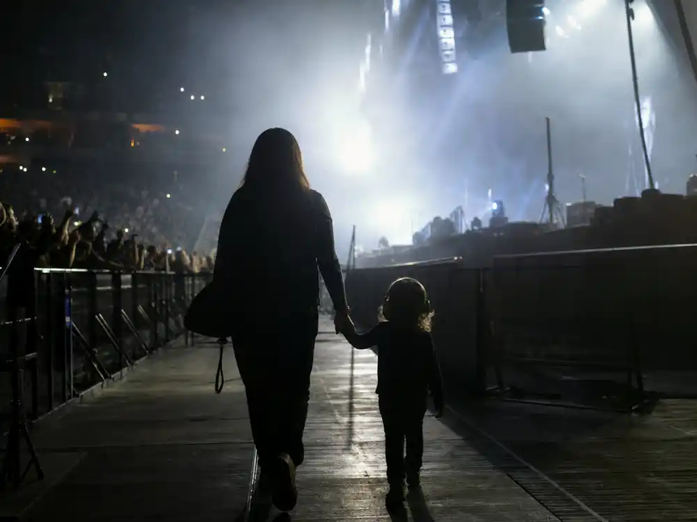 Child silhouette from behind walking toward arena stage lights in Beyonce twins Rumi and Sir rare appearances — Cowboy Carter Tour cameo mood without faces