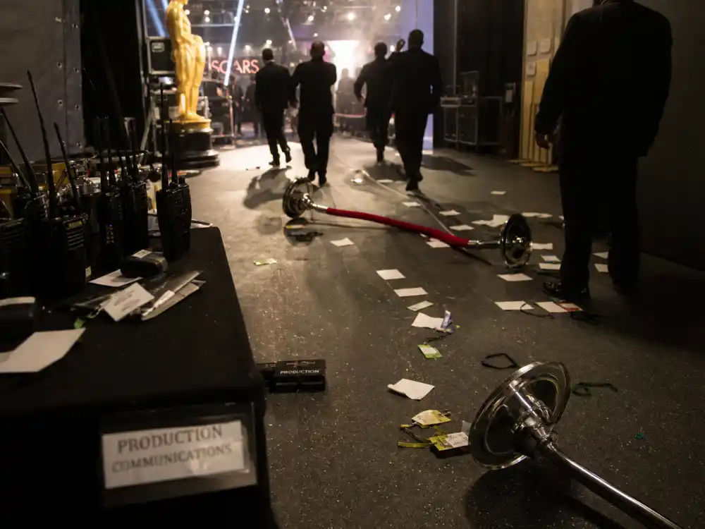 Chaotic backstage awards corridor with security and scattered press credentials after live ceremony incidents ranked among the biggest award show scandals ever