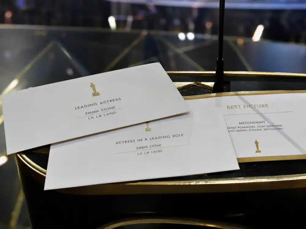 Wrong Best Picture envelopes on a golden awards podium represent Envelopegate among the biggest award show scandals ever in Oscar ceremony history