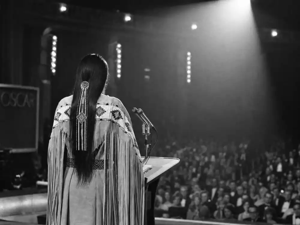 Woman silhouette in traditional dress at a vintage Oscar podium evokes Sacheen Littlefeather protest among the biggest award show scandals ever at the Academy Awards