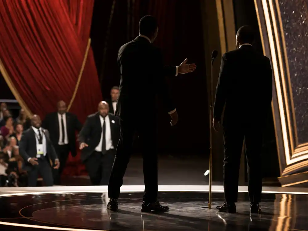 Anonymous tuxedo silhouettes on an Oscar stage near a microphone capture tension behind the biggest award show scandals ever including live telecast confrontations