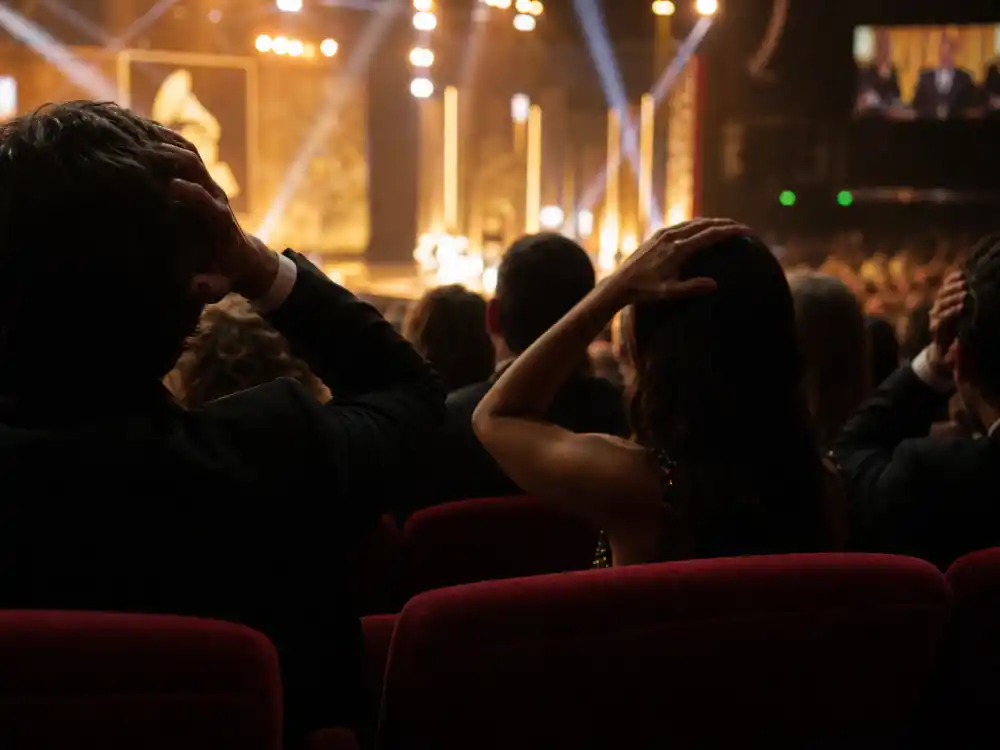 Silhouetted audience members reacting in theatre seats represent fan outrage when the biggest Grammy snubs of all time unfold live on CBS