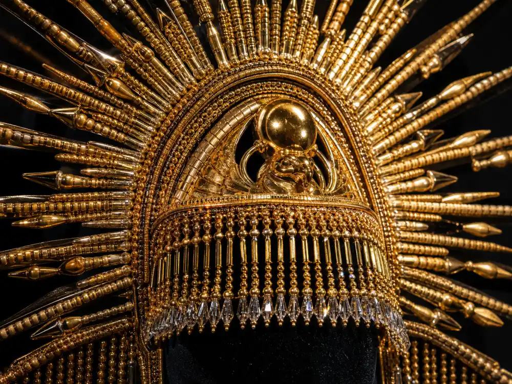 Close-up gold sun-ray ceremonial headpiece with crystal fringe and bugle beads at heart of Billy Porter sundial hat Met Gala search legend
