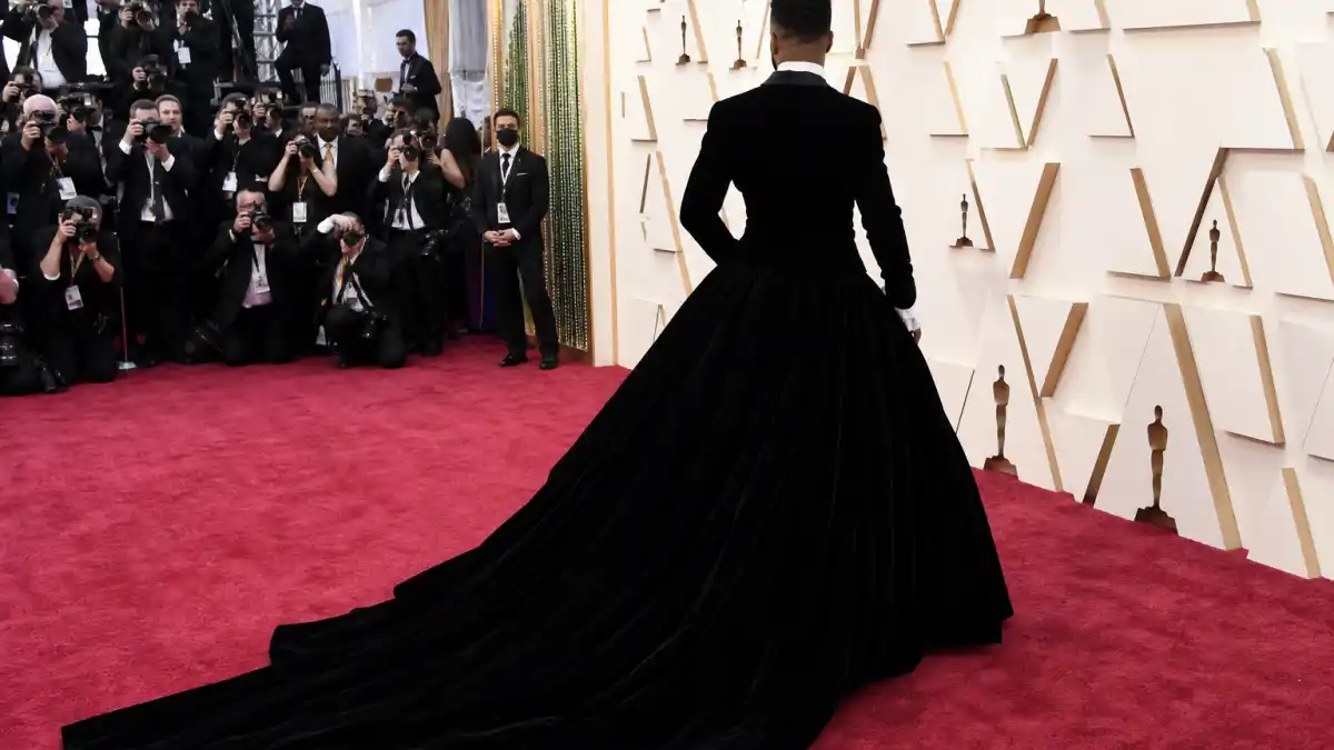 Billy Porter tuxedo gown Oscars history — iconic black velvet tuxedo jacket with voluminous ball gown skirt photographed from behind on 2019 Academy Awards red carpet