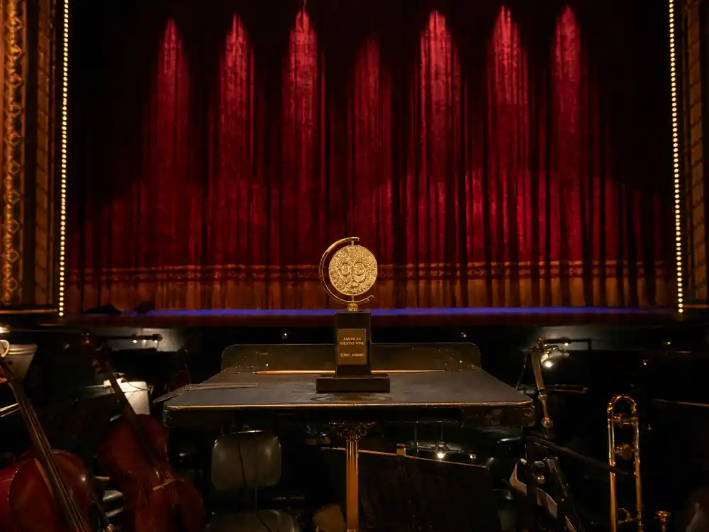 Broadway orchestra pit with golden Tony Award trophy tracking the most Tony Awards won by a show ceremony-night totals