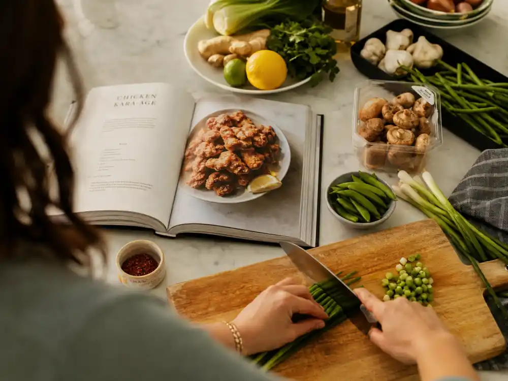 Cookbook kitchen scene with open recipe book and fresh ingredients for Brooklyn Beckham nepo baby ventures What Is in the Fridge editorial without identifiable faces