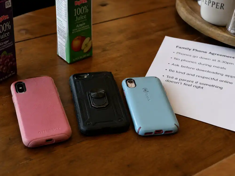 Children smartphones face-down on kitchen table in Carter family privacy rules for kids — digital boundaries for Blue Ivy Rumi and Sir