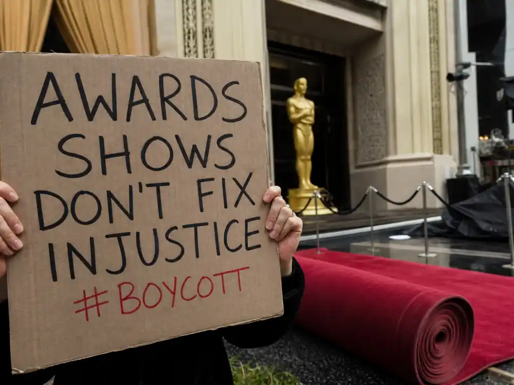 Anonymous hands holding protest signs outside a vacant awards red carpet capture why celebrities who boycotted award shows skipped telecasts in solidarity