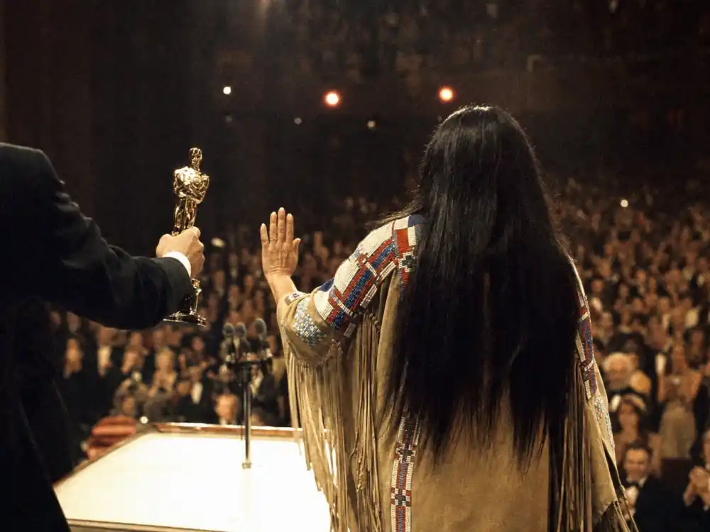Vintage Oscar podium silhouette in traditional dress evokes Sacheen Littlefeather protest among celebrities who criticized the Oscars in 1973