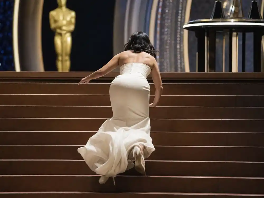 Anonymous gown silhouette tripping on Oscar stairs recalls Jennifer Lawrence 2013 fall among celebrities who fell on stage at award shows