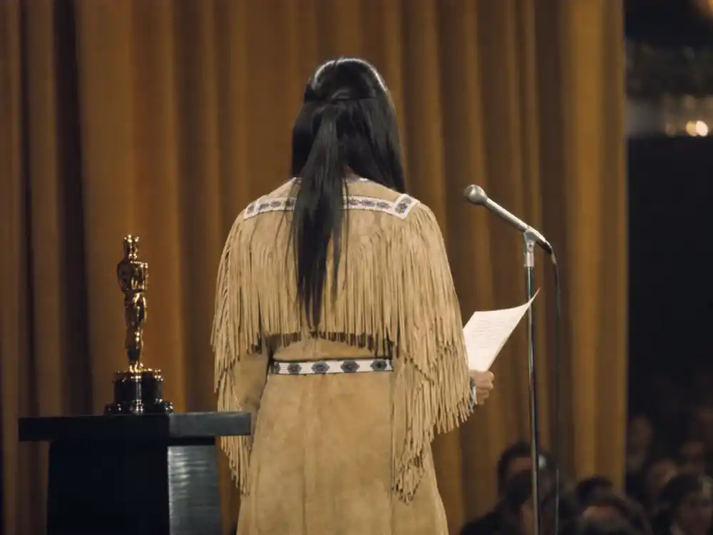 Vintage Oscar podium silhouette in traditional dress evokes Sacheen Littlefeather 1973 protest among celebrities who got political at award shows